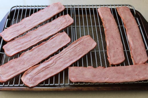 Running bacon under cold water helps to reduce its shrinking. Add a little stevia to each slice and candied bacon is born!