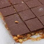 Never again will you miss a store bought Snickers! These chocolate caramel peanut bars are simple to make, gluten free and low in carbs. No baking necessary! Simply layer peanuts, caramel and chocolate for the ultimate keto chocolate bar.