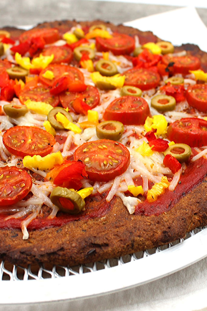 Tomatoes, peppers and olives on a dairy-free vegan pizza crust