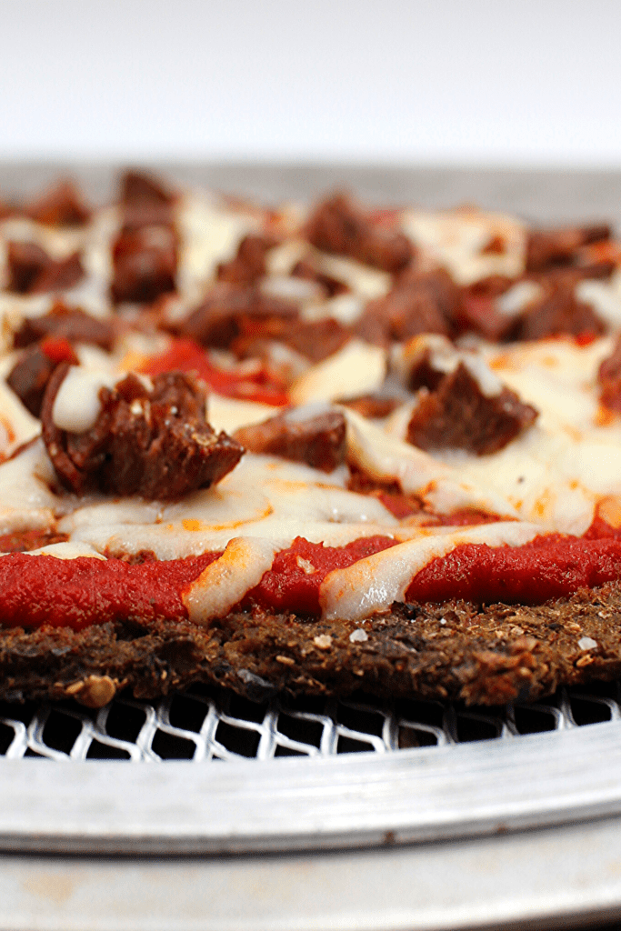Plant-based pizza crust topped with cheese and sausage
