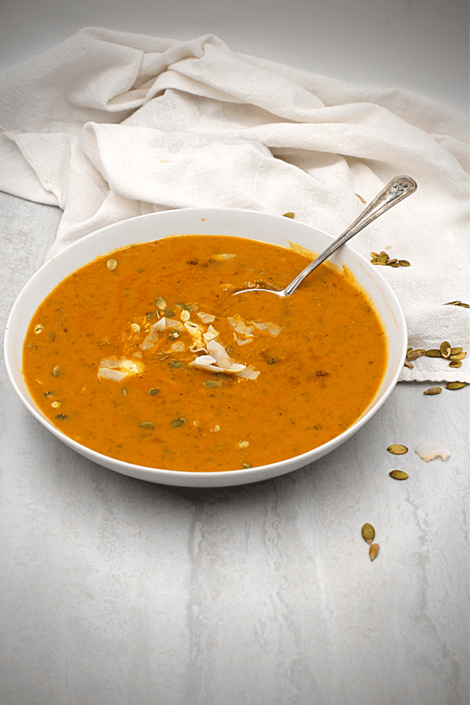 pumpkin seeds on top of a bowl of dairy-free creamy pumpkin curry soup