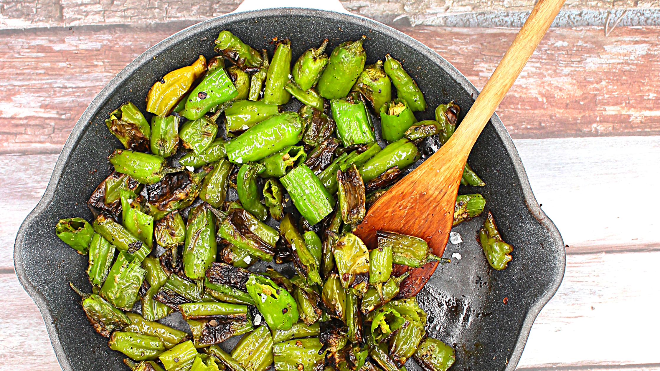 shishito peppers getting charred in a skillet
