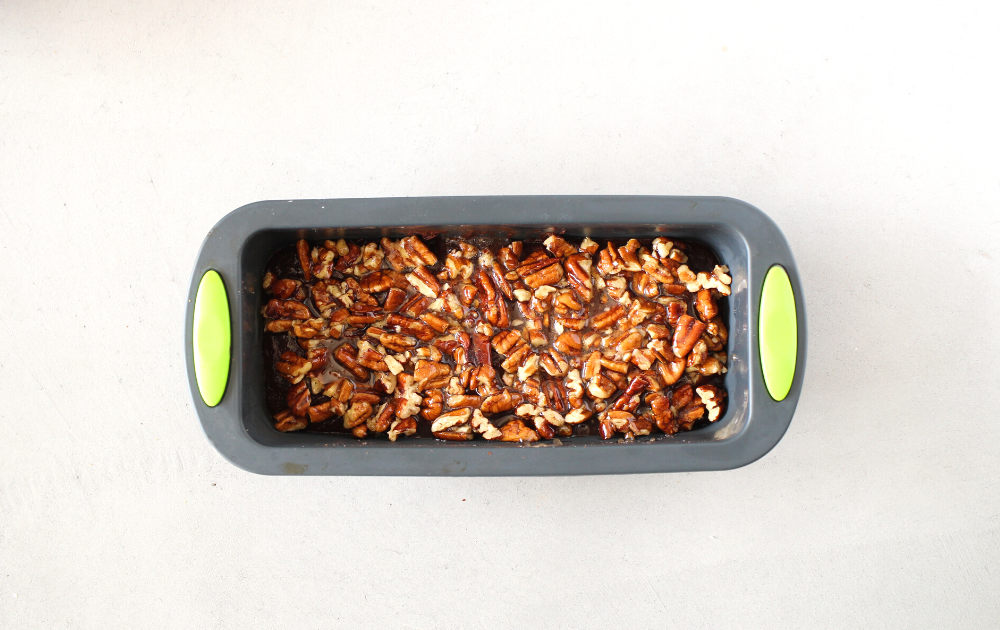 Instructions - Step3 - spread half the chocolate into a loaf pan and place in the freezer. Stir together the caramel and chopped pecans and spread it over chocolate fudge layer