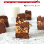 keto turtle fudge that has 2 thick layers of chocolate sandwiching a layer of caramel pecan