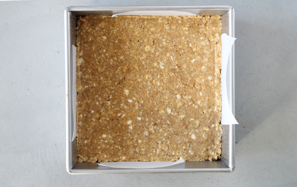 Instructions - Remove 1 ½ cups of the mixture and set it aside.  Press the remaining mixture into the bottom of a parchment-lined 8 x 8-inch baking pan.