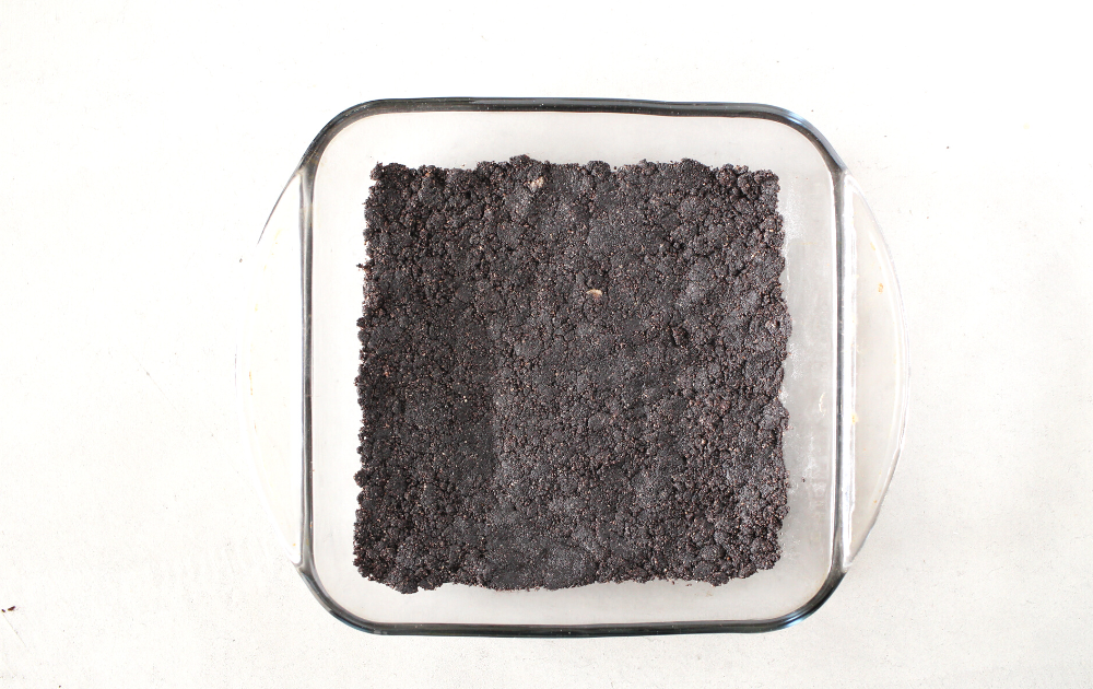 Add all the keto crust ingredients into a skillet and cook, stirring constantly for 5 minutes. Remove and press the mixture into the bottom of an 8 x 8 inch pan. Place in the freezer to cool.