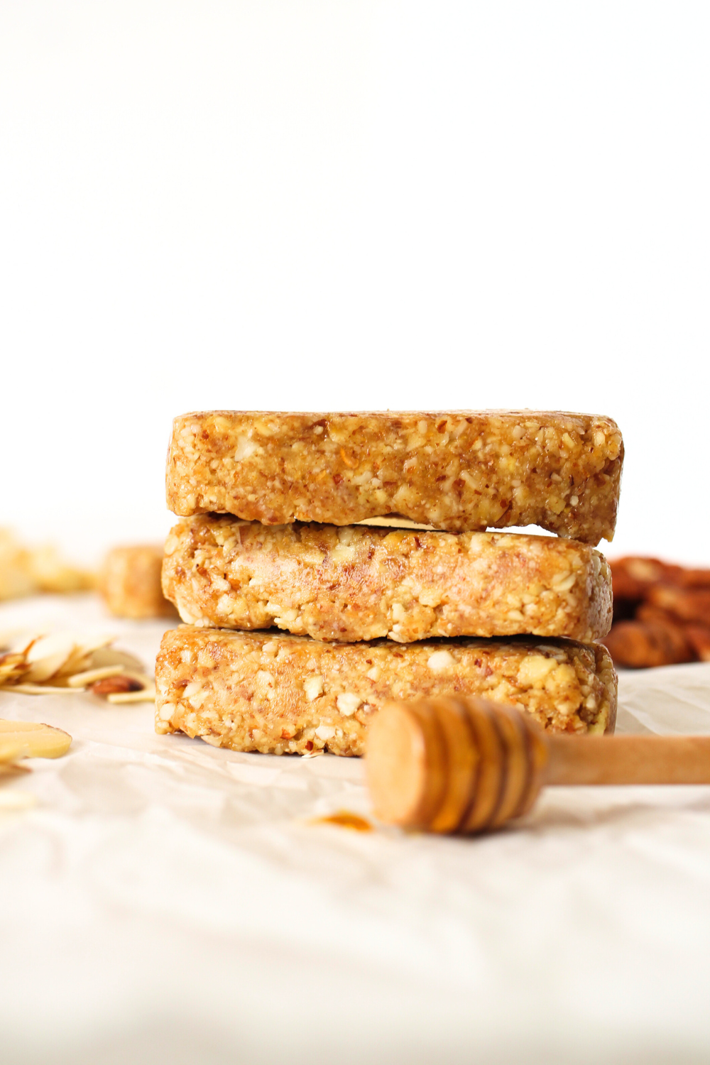 3 homemade keto fasting bars stacked on top of each other wtih a wooden honey dipper stick with honey on it