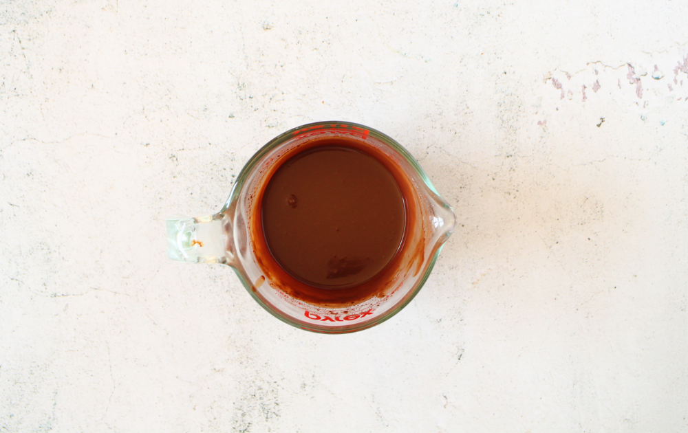 a measuring cup with sugar-free chocolate melted with cream for making the keto ganache