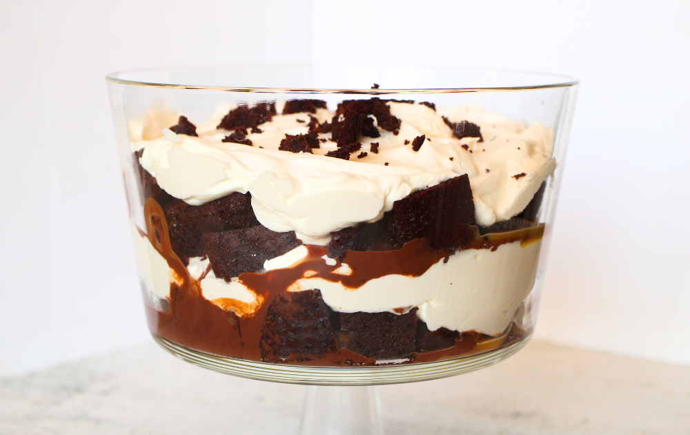 a trifle bowl with alternating layers of gluten-free chocolate cake, keto chocolate ganache, sugar-free caramel sauce and keto whipped cream.
