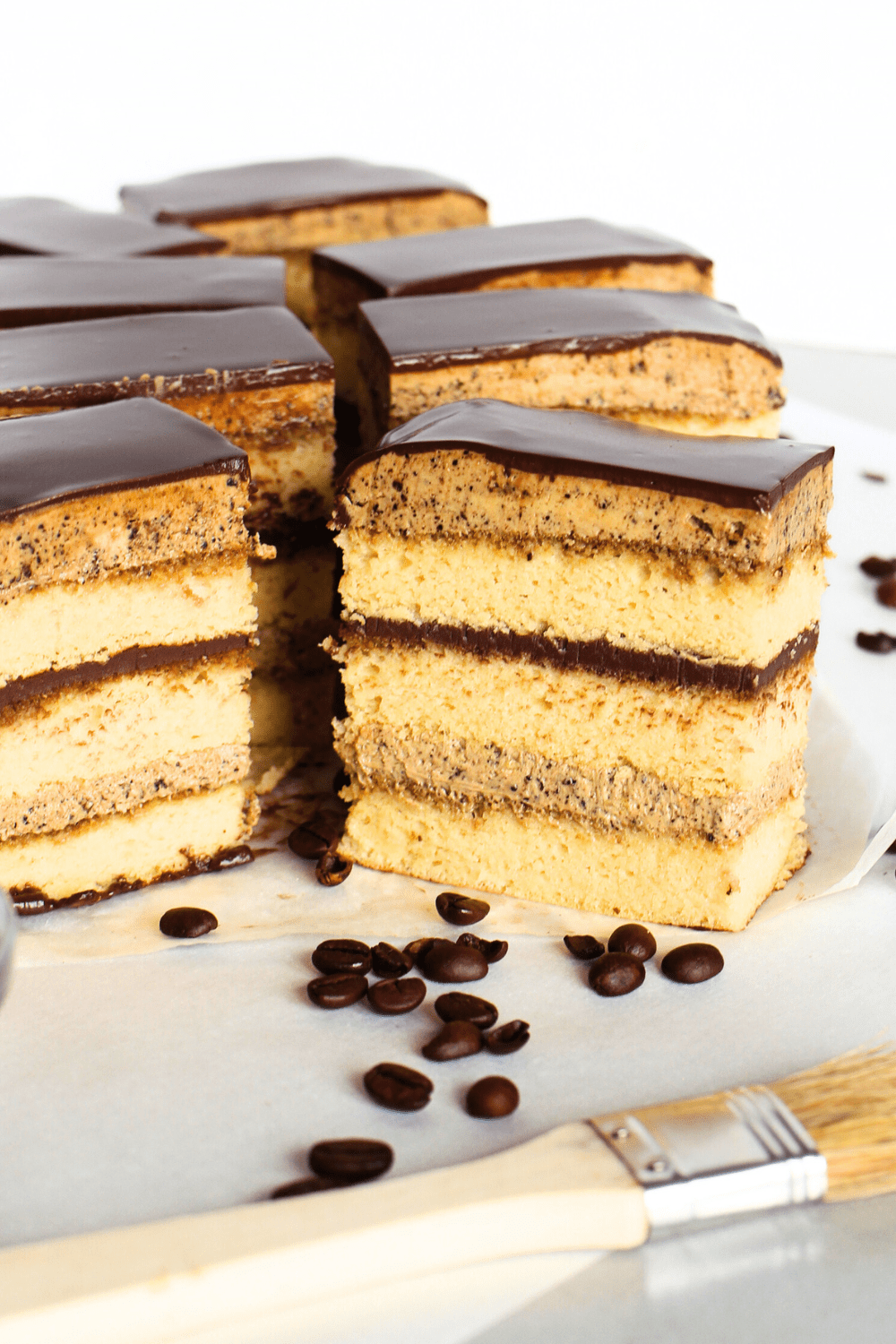 angled view of gluten-free opera cake with espresso coffee beans scattered