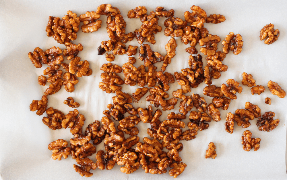 top view of sugar-free candied spiced nuts spread on a sheet of parchment paper to cool and crisp