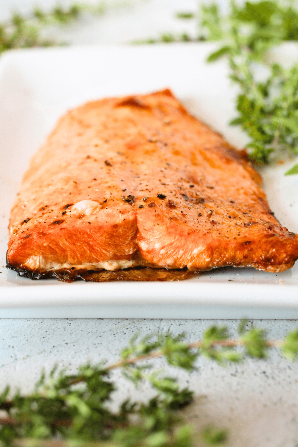 front view of cooked salmon in an air fryer with a keto bang bang sauce and herbs scattered throughout