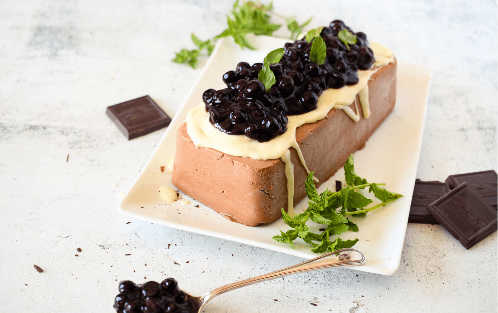 angled top view of keto chocolate semifreddo being served with sugar-free white chocolate ganache, blueberries and fresh mint