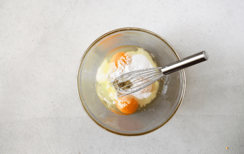 top view of a bowl with allulose, eggs and salt before being whisked