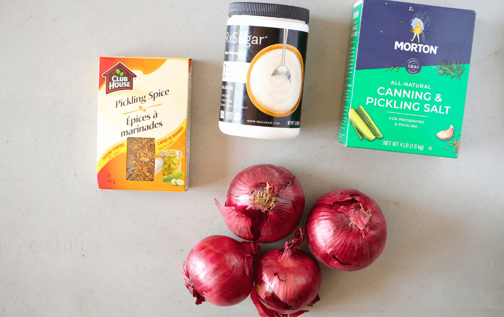 top view of ingredients needed for sugar-free pickled red onions include red onions, pickling salt, pickling spices and allulose