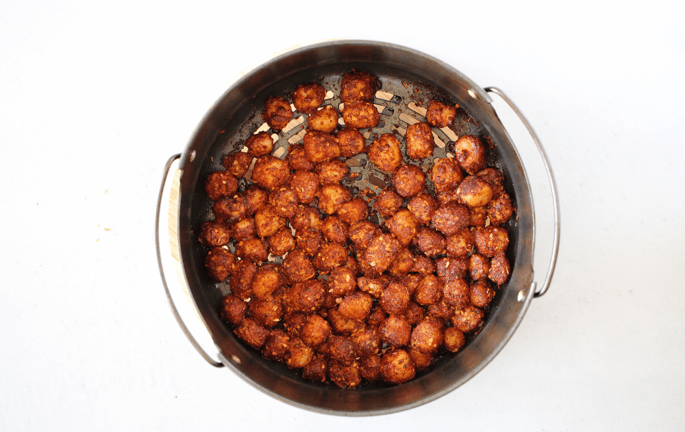 top view of an air fryer basket with spicy cooked bay scallops