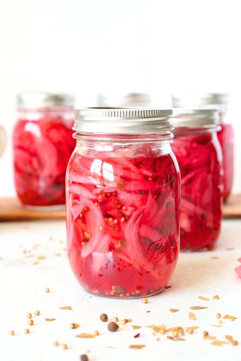 front view of sugar-free pickled onions in a jar after being canned.  Pickling spices scattered throughout