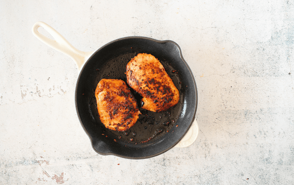 top view of ovenproof skillet with browned chicken breast for Whole30 Garlic Mushroom Chicken recipe