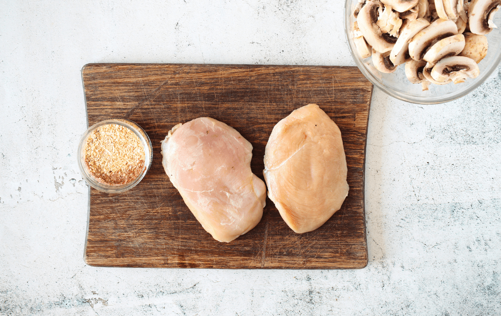 top view of Keto Garlic Mushroom Chicken ingredients which include salt, pepper, garlic, mushrooms, chicken and smoked paprika