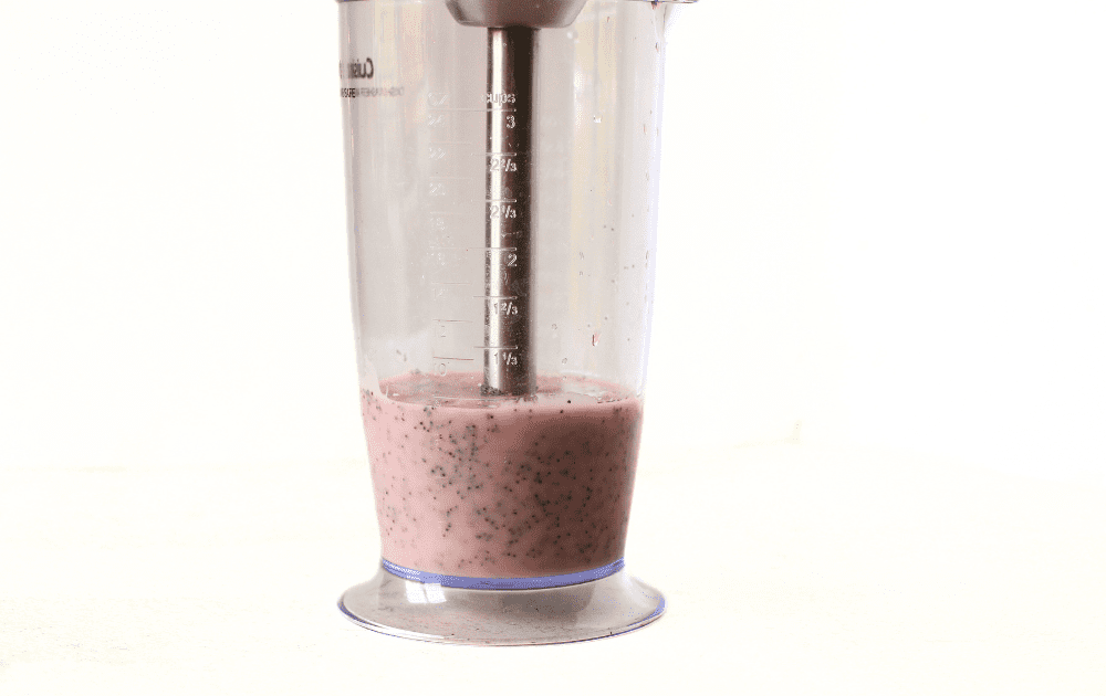 an immersion blender in a bowl being used to emusify this keto poppy seed salad dressing