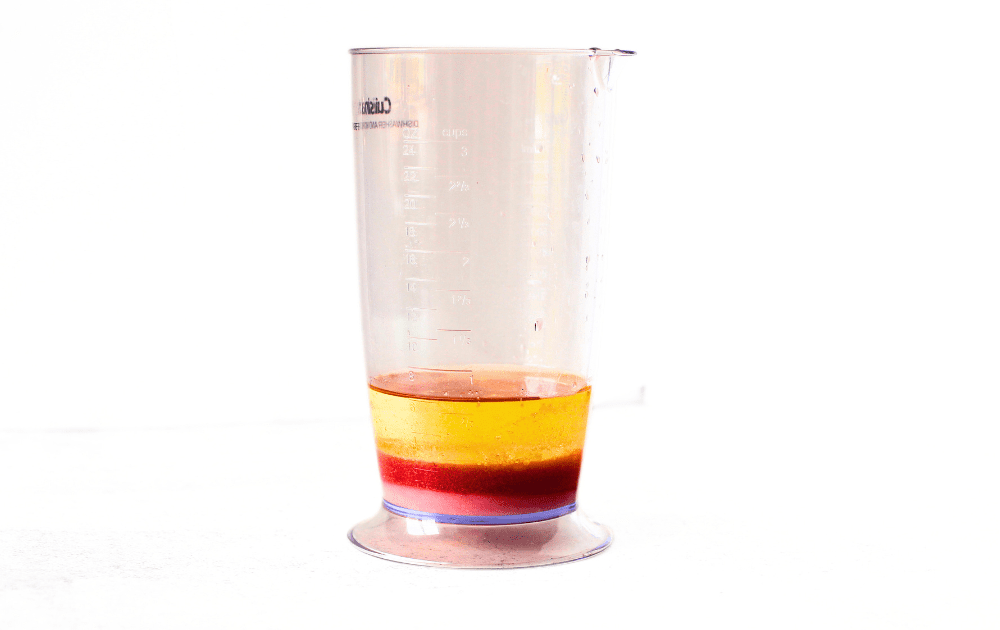 an immersion blender bowl filled with layers of red wine vinegar, dried mustard, poppy seeds, oil and sugar-free sweetener to make a sugar-free poppy seed dressing