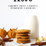 5 Chewy Keto Pumpkin cookies stacked on top of each other with a jug of milk behind the cookies. pumpkin, cinnamon and gold spoons are scattered around the sugar-free pumpkin cookies.