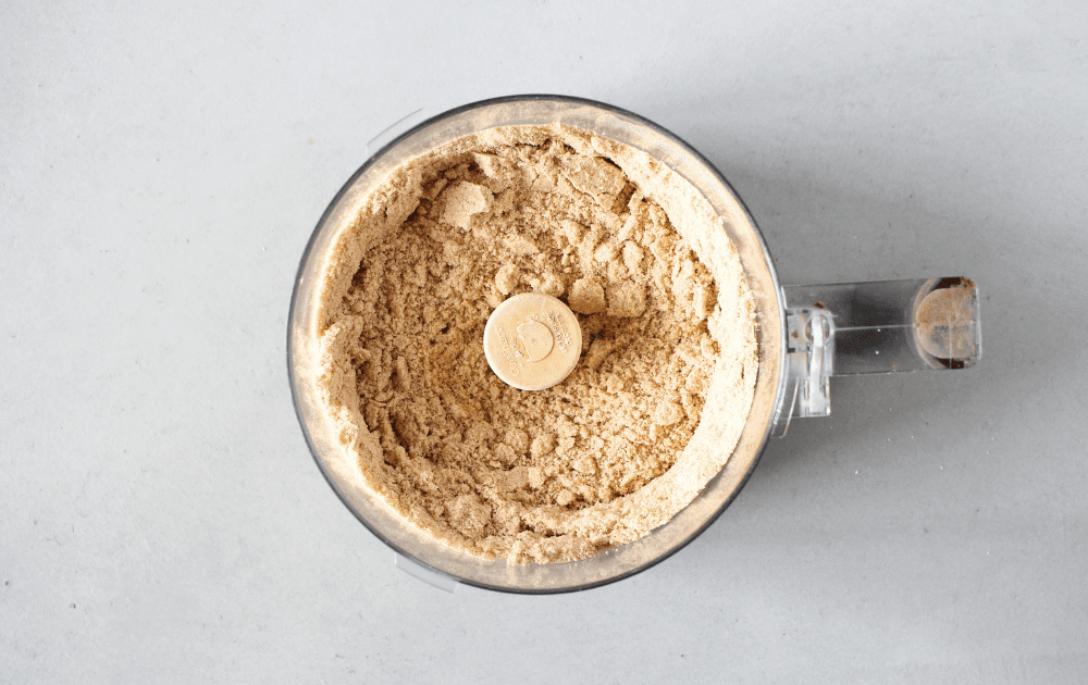 top view of the bowl of a food processor that contains almond flour, flaxseed meal, pumpkin pie spice, salt, baking soda and baking powder.