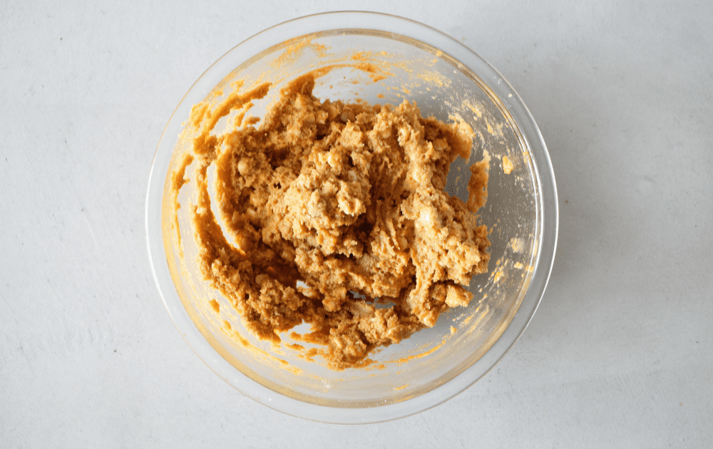 top view of a mixing bowl with the wet pumpkin cookie ingredients being mixed into the dry keto pumpkin cookie mix.
