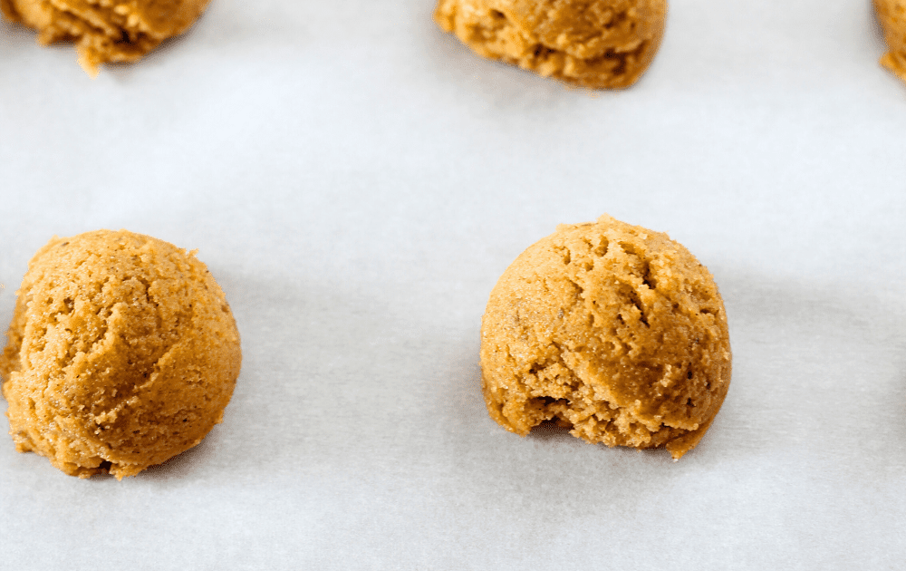 view of keto pumpkin cookie dough portioned into 1 tablespoon balls and placed on a parchment lined cold baking sheet.