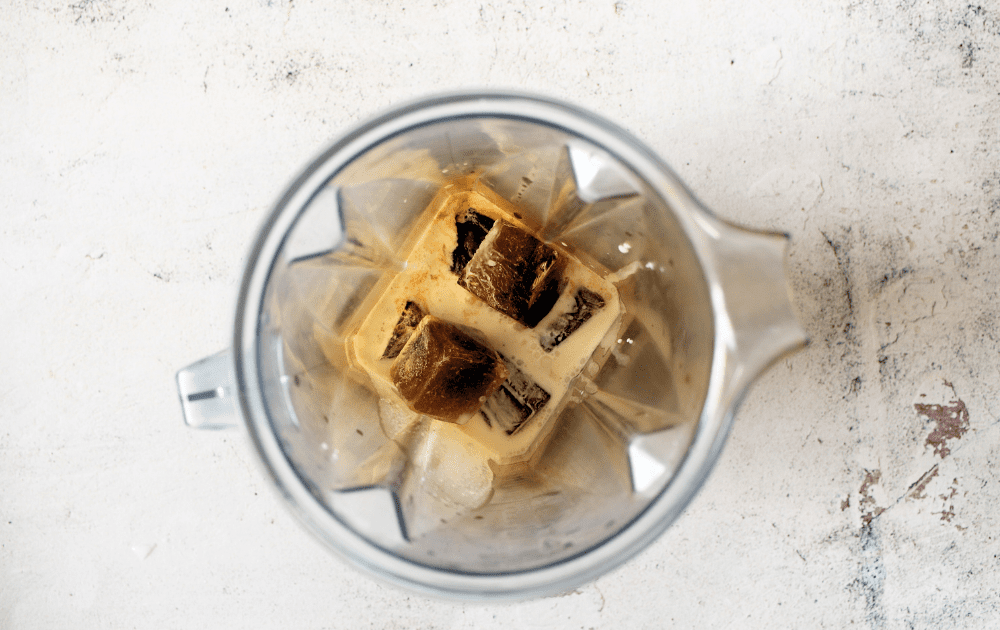 a high speed blender filled with coffee ice cubes, coffee, heavy cream and homemade vanilla sugar-free syrup