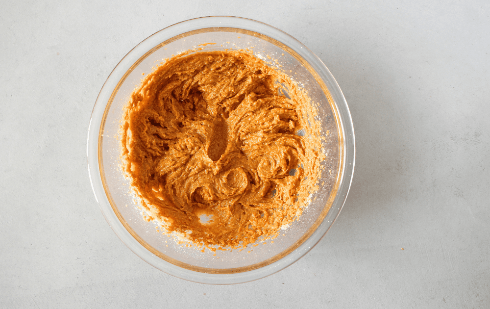 top view of a mixing bowl with pumpkin, almond flour, baking soda, salt, and pumpkin pie spice beated until smooth