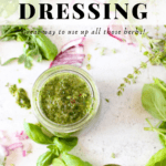 a jar of keto fresh herb salad dressing with scattered herbs, a spoon and sliced red onions scattered througout