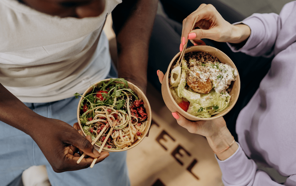 a picture of two sets of hands eating bowls of healthy foods including healthy eating gift ideas