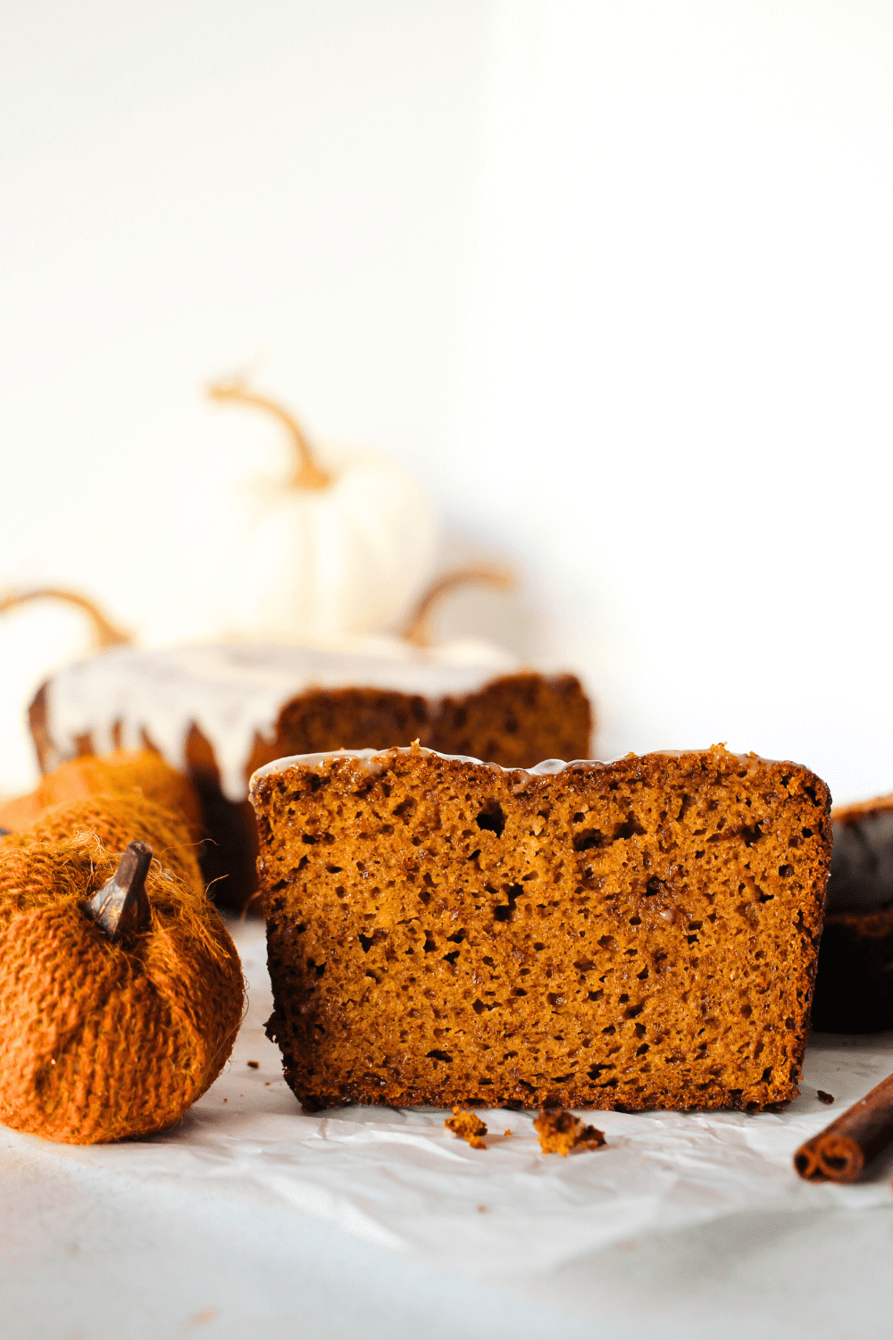 a slice of keto pumpkin bread with sugar-free frosting and a decorative pumpkin on the side