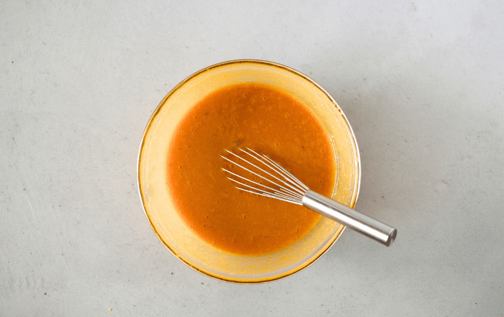 top view of a mixing bowl with pumpkin, sugar-free sweetener, coconut oil with a whisk in the bowl