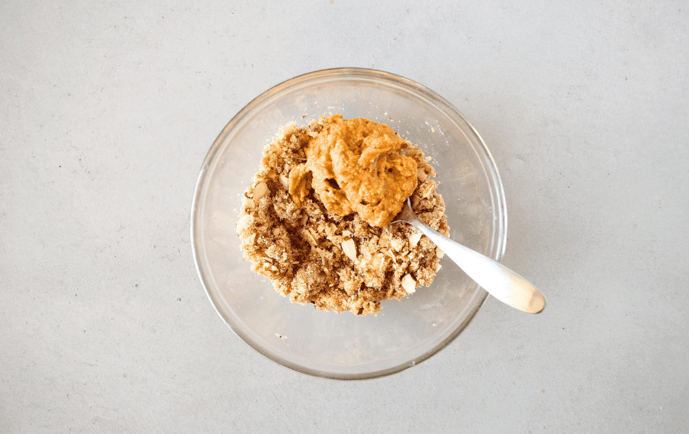 top view of the keto coffee cake crumb topping being mixed with the ¼ cup of keto pumpkin cake using a spoon