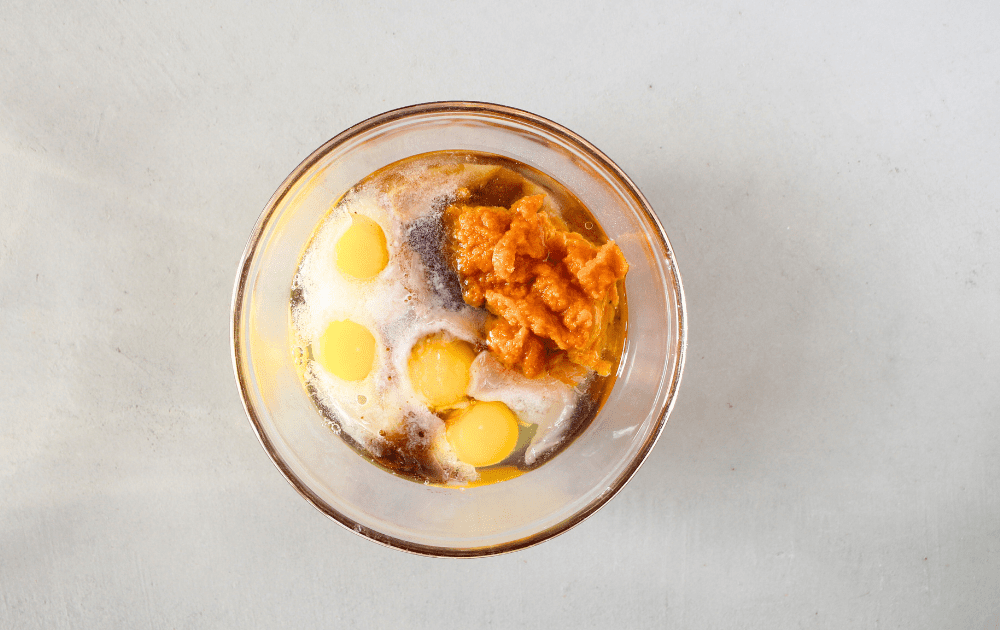 top view of a small mixing bowl with pumpkin, eggs, oil, sweeteners before being whisked together for this easy keto quick bread recipe