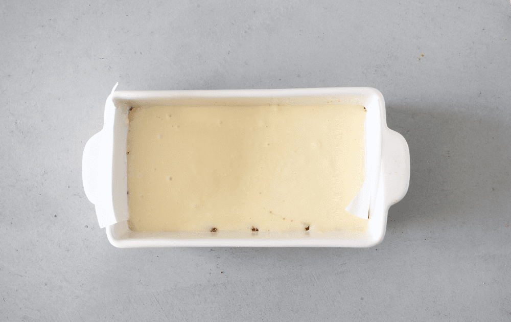 top view of a loaf pan with a keto crust layer and topped with a keto cheesecake bar layer