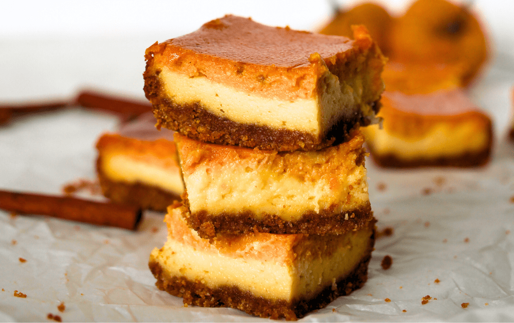 side view of 3 stacked sugar-free pumpkin cheesecake bars with cinnamon sticks