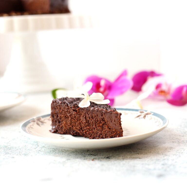 a slice of keto chocolate flourless cake made without nuts served on a plate with flower decorations