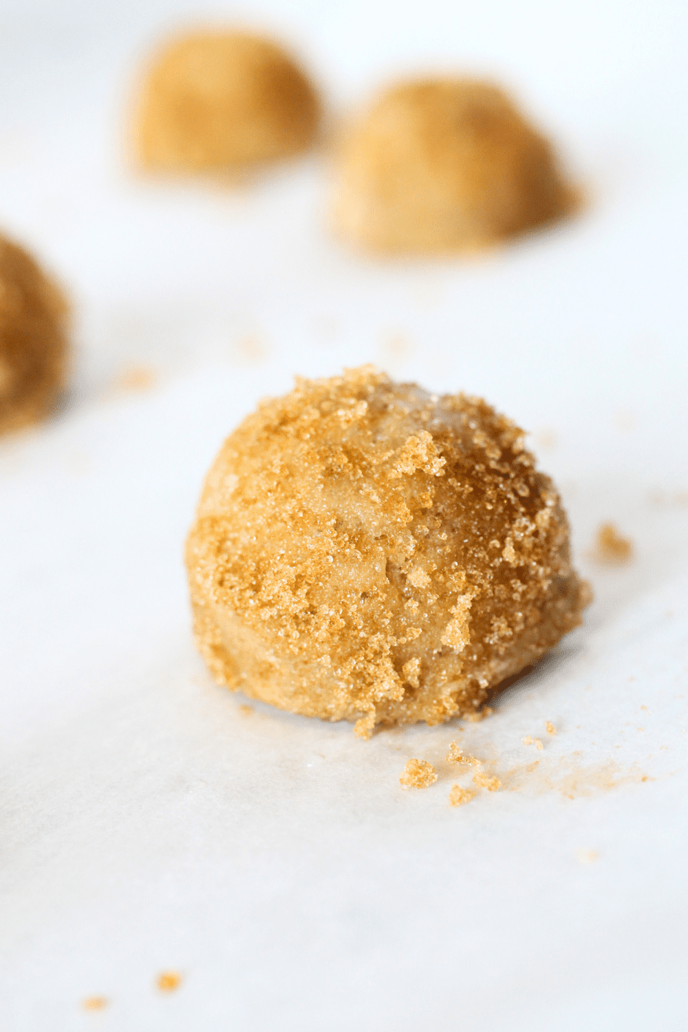 a keto maple ginger cookie dough ball on a baking sheet that has been covered with a piece of parchment paper.