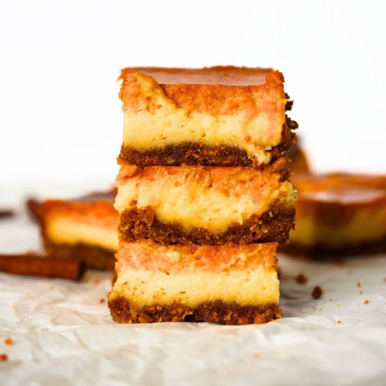 3 keto pumpkin chiffon cheesecake bars stacked on top of each other with a cinnamon stick in the background