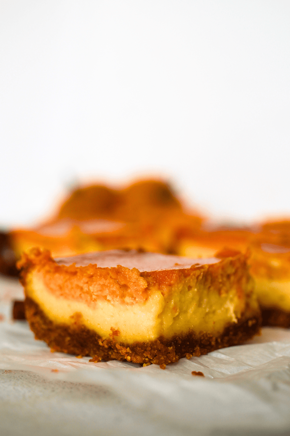 a keto cheesecake pumpkin bar with 3 distinct sugar-free layers of crust, keto cheesecake and sugar-free pumpkin bars