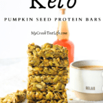 keto copycat warrior bar made with pumpkin seeds stacked on top of each other with a cup of coffee and pumpkin seeds scattered around the keto pumpkin seed protein bars
