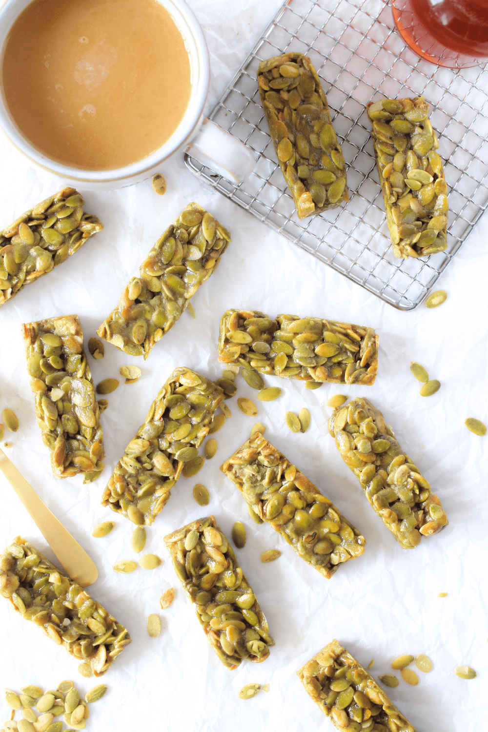 sugar-free protein bars made with pumpkin seeds scattered with a cup of coffee and sugar-free syrup