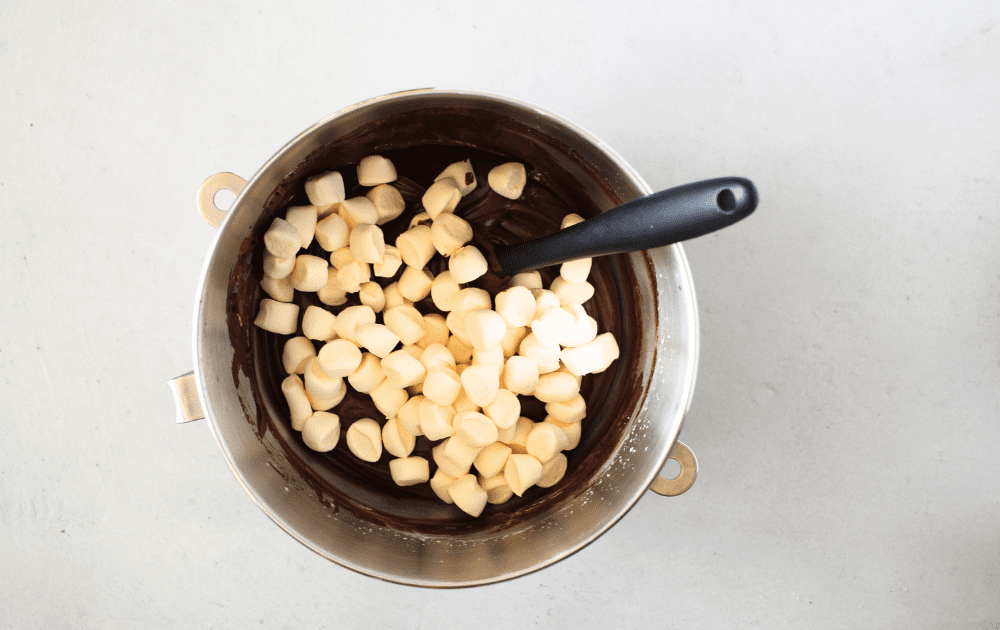 top view of a mixing bowl with whipped heavy cream blended with sugar-free chocolate ganache and sugar-free homemade marshmallows being folded into the keto frozen hot chocolate pie