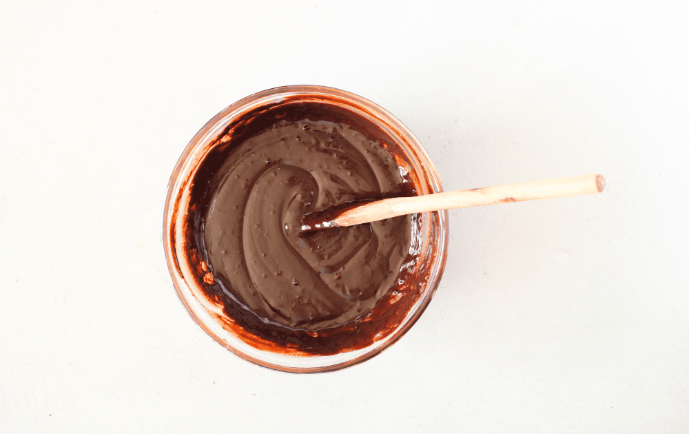 top view of a mixing bowl with melted sugar-free chocolate using heavy cream and adding allulose