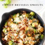 top view of a skillet filled with keto cheesy Brussels sprouts casserole with bacon, mushroom and onion. Brussels sprouts scattered around the easy keto side dish