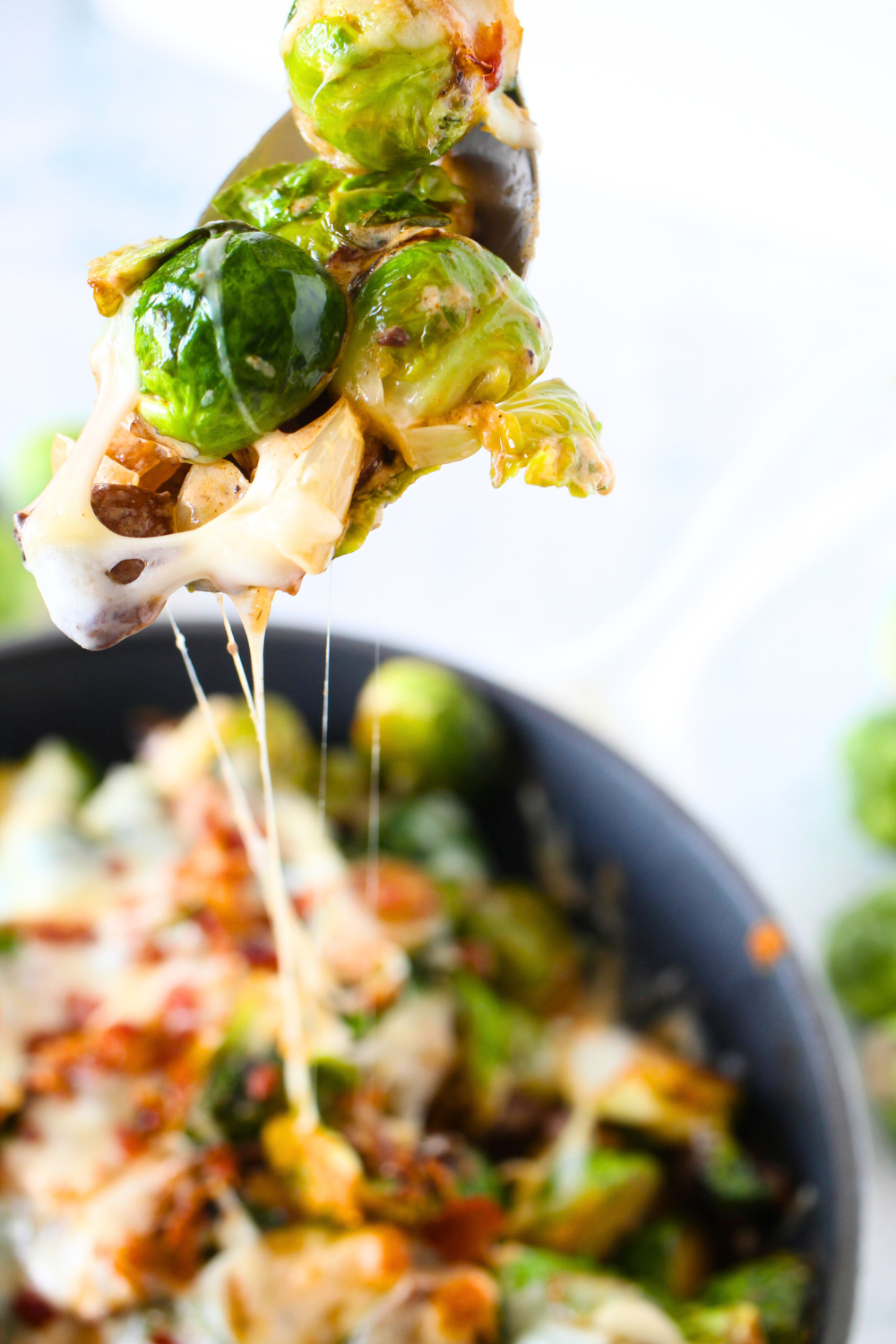 a view of keto cheesy Brussels sprouts casserole with melted cheese on a serving spoon