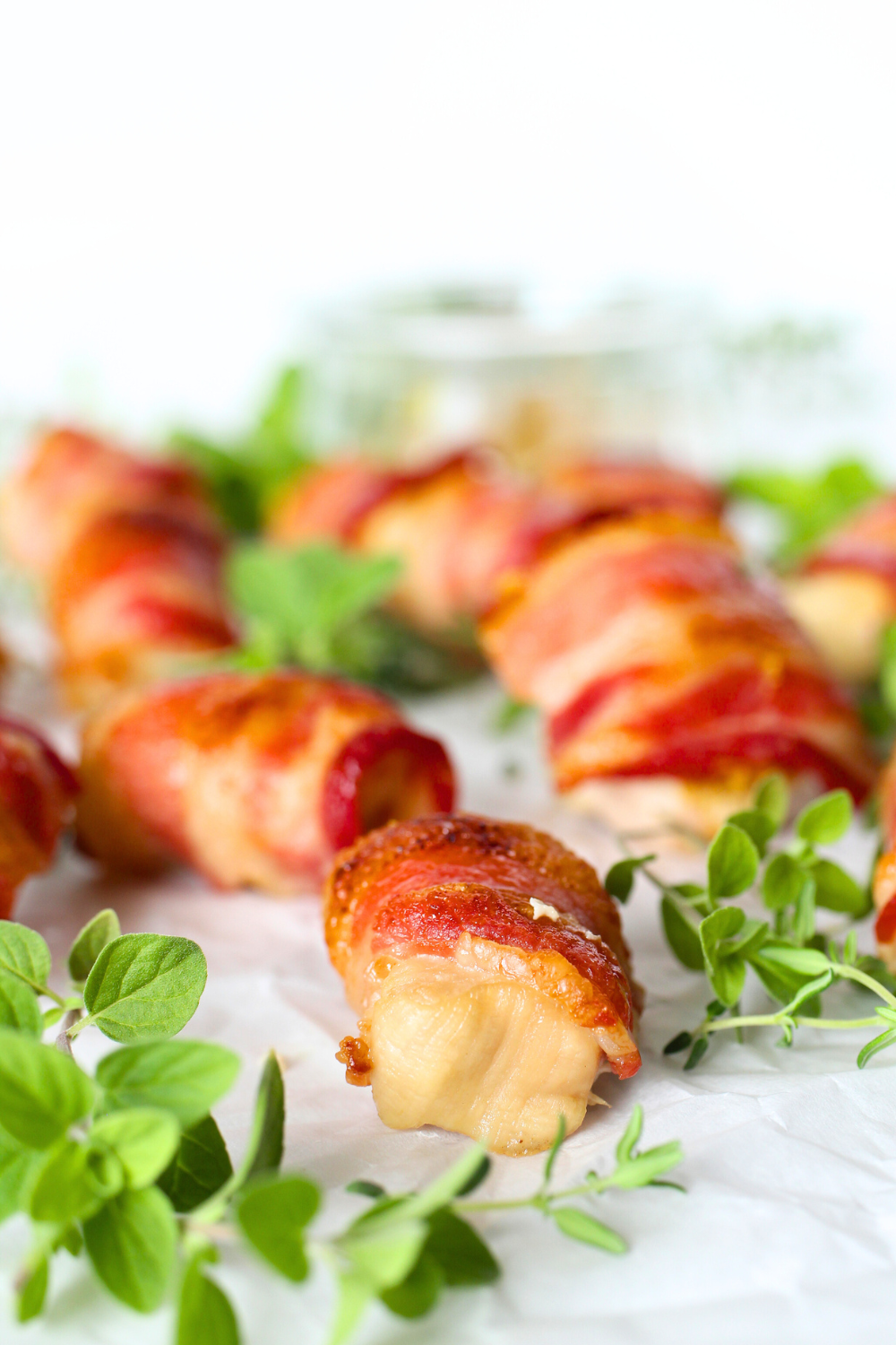 keto bacon-wrapped mustard bites on a platter with fresh cut herbs as decoration